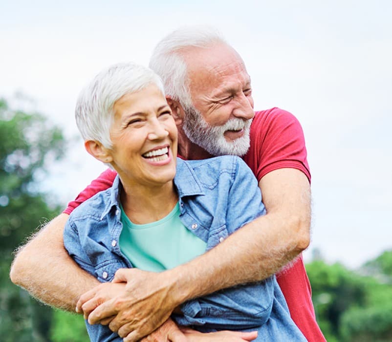A retired couple embracing outdoors